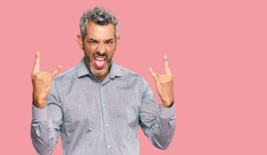 Orta yaşlı, gri saçlı, günlük kıyafetler giyen çılgın bir ifadeyle bağıran elleri havada rock sembolü yapan bir adam. Müzik yıldızı. ağır kavram. 