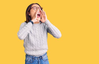 Genç ve güzel Çinli kız günlük kıyafetler giyip elleri ağızda bağırarak bağırıyor. 