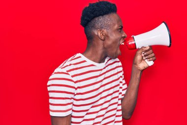 Genç Afrikalı adam kızgın bir şekilde megafondan bağırıyor.