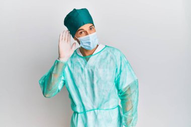 Cerrah üniforması ve tıbbi maske takan genç yakışıklı bir adam. Kulağından kulağa gülümsüyor. Dedikoduları ve dedikoduları dinliyor. Sağırlık kavramı. 