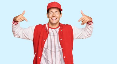 Beyzbol üniforması giyen yakışıklı, kendine güveni olan, kendini gururlu ve mutlu gösteren beyaz bir adam.. 