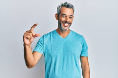 Orta yaşlı, gri saçlı, günlük kıyafetler giyen, gülümseyen, kendine güvenen, el hareketi yapan, parmaklarıyla işaret yapan ve kameraya bakan bir adam. ölçüm kavramı. 