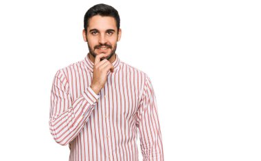 İş gömleği giyen genç İspanyol adam kameraya kollarını kavuşturup gülümseyerek ve çenesini kaldırarak bakıyor. Olumlu düşünmek. 