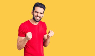 Sakallı, sıradan tişörtler giyen, kolları havada ve gözleri kapalı zaferi kutlayan genç yakışıklı bir adam. Kazanan konsept. 