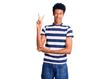 Genç Afro-Amerikalı sıradan kıyafetler giyen, gülen yüzlü, kameraya göz kırpan zafer işareti yapan genç bir adam. İki numara.. 