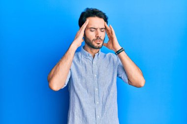 Genç İspanyol bir adam zarif bir yaz gömleği giyiyor. Eli başının üstünde. Stres yüzünden baş ağrısı çekiyor. migren ağrısı. 