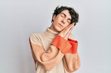 Kış süveteri giyen İspanyol genç adam uyuyordu. Yorgun düşler görüyordu ve elleriyle poz veriyordu. Gözleri kapalıyken gülümsüyordu.. 