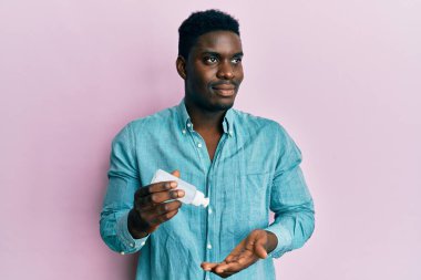 El dezenfektanı jeli kullanan yakışıklı zenci. Gülümsüyor, yan tarafa bakıyor ve düşünüyor.. 