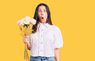 Genç, güzel, esmer bir kadın elinde bir buket çiçek tutuyor. Korkmuş ve şaşkına dönmüş ağzı açık, şaşırmış, inançsız bir yüz. 