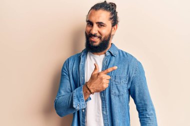 Genç Arap adam gündelik giysiler giyiyor. Gülümsüyor, elleri ve parmakları yana doğru uzanıyor. 