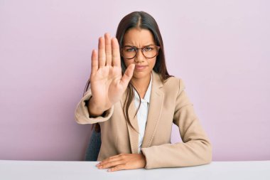 Ofiste çalışan güzel İspanyol kadın avuç içiyle şarkı söylemeyi kesiyor. Yüzünde olumsuz ve ciddi bir jest olan uyarı ifadesi. 