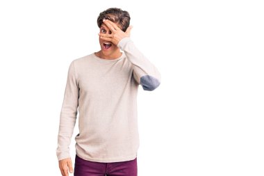 Gündelik kıyafetler giyen genç yakışıklı adam şok içinde yüzünü ve gözlerini kapayarak utangaç ifadesiyle parmaklarının arasından bakıyor.. 