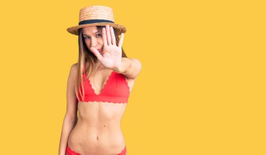 Güzel esmer, bikini giyen genç bir kadın avucuyla şarkı söylemeyi kesiyor. Yüzünde olumsuz ve ciddi bir jest olan uyarı ifadesi. 