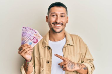 Ellerinde 50 Meksika pezosu olan yakışıklı bir adam. Gülümsüyor, mutlu mesut parmakla işaret ediyor. 