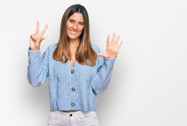 Gündelik kıyafetler giyen genç bir kadın sekiz numarayı gösterip işaret ederken kendinden emin ve mutlu bir şekilde gülümsüyor.. 