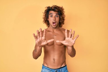 İspanyol asıllı genç adam korku ifadesinden korkmuş ve dehşete düşmüş halde ayakta duruyor. El kol hareketi yapmayı kes, şok içinde bağırmayı kes. panik konsepti. 