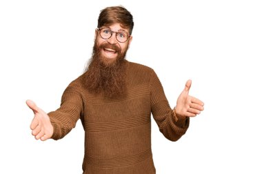 Genç İrlandalı kızıl elbiseli ve gözlüklü adam kameraya sarılıp gülümsüyor. Mutluluğu kucaklayan neşeli bir ifade.. 