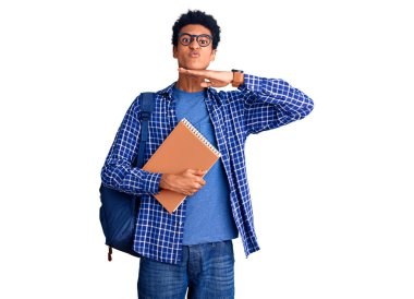 Genç Afro-Amerikalı bir adam sırt çantası takıyor. Kitabı tutuyor. Elinde bıçakla boğazını kesiyor. 