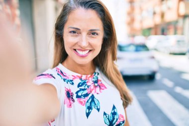 Genç İspanyol kadın gülümsüyor. Mutlu bir şekilde şehrin kamerasında selfie çekiyor.