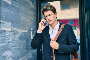 Kafkasyalı genç iş adamı ciddi bir ifadeyle şehirdeki akıllı telefondan konuşuyor..