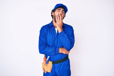 Kıvırcık saçlı yakışıklı genç adam ve ayı dokuma ustası üniforması. Ağzı eliyle kapatmaktan sıkılmış. Huzursuz ve uykulu.. 