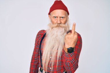 Old senior man with grey hair and long beard wearing hipster look with wool cap showing middle finger, impolite and rude fuck off expression 