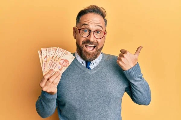 ハンサムな中世の男を保持100メキシコペソ紙幣指差す親指上へ側笑顔幸せとともにオープン口 — ストック写真