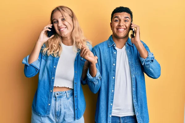 stock image Young interracial couple having conversation talking on the smartphone screaming proud, celebrating victory and success very excited with raised arm 