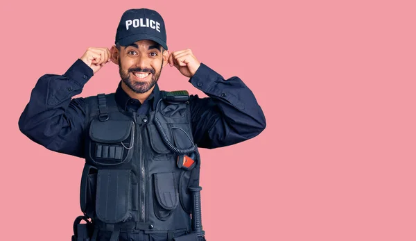 Joven Hispano Vestido Con Uniforme Policía Sonriendo Tirando Las Orejas —  Fotos de Stock