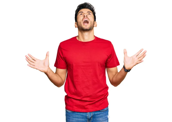 カジュアルな赤いTシャツを着た若いハンサムな男が狂った叫び 積極的な表現と腕を上げて叫びました フラストレーションコンセプト — ストック写真