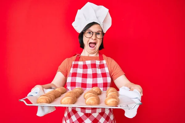 Bruneta Žena Downovým Syndromem Pekařské Uniformě Držící Domácí Chléb Rozzlobená — Stock fotografie