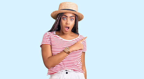 Young African American Woman Braids Wearing Summer Hat Surprised Pointing — Stock Photo, Image