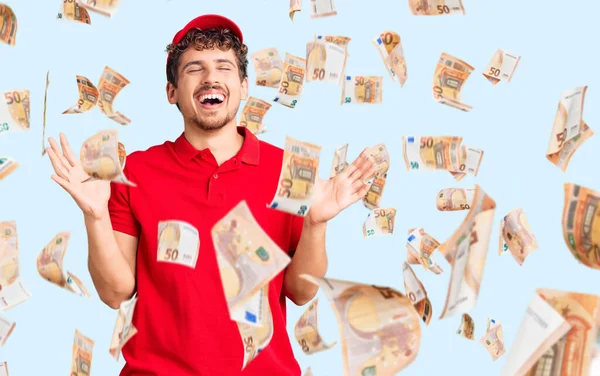 Kıvırcık saçlı, teslimat üniforması giyen genç ve yakışıklı bir adam başarının çılgınlığını kollarını kaldırmış ve gözlerini kapatmış heyecanlı çığlıklar atarak kutluyor. Kazanan konsept