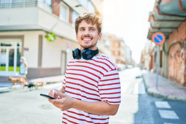 Jeune Homme Caucasien Souriant Heureux Portant Des Écouteurs Utilisant Smartphone — Photo