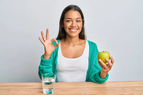 美丽的他惊慌失措的女人喝着一杯水 吃着热苹果 用手指做手势 微笑着表示友善的手势 这是个极好的象征 — 图库照片