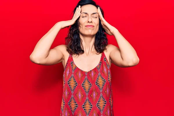 Genç, güzel, İspanyol bir kadın. Elleri başının üstünde, günlük kıyafetler giyiyor. Stres yüzünden baş ağrısı çekiyor. migren ağrısı. 