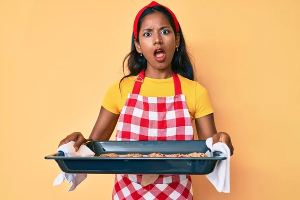 Молода Індійська Дівчина Формі Пекарні Тримає Домашнє Печиво Шоковому Обличчі — стокове фото