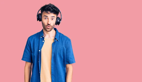 Joven Hispano Escuchando Música Usando Auriculares Asustado Sorprendido Con Boca —  Fotos de Stock