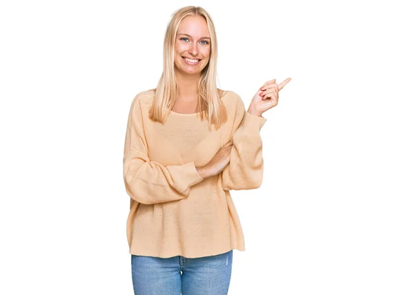 Młoda Blondynka Luźnych Ubraniach Dużym Uśmiechem Twarzy Wskazując Ręką Palcem — Zdjęcie stockowe