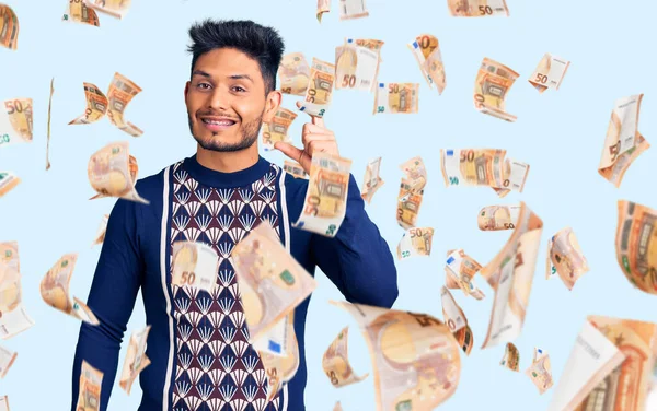 Yakışıklı Latin Amerikalı genç adam günlük kışlık süveter giyiyor gülümsüyor ve kendine güvenen el hareketleriyle küçük boy işareti yapıyor parmaklarıyla ve kamerayla bakıyor. ölçüm kavramı.