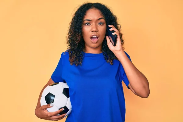 Jovem Afro Americana Segurando Bola Futebol Falando Smartphone Face Choque — Fotografia de Stock