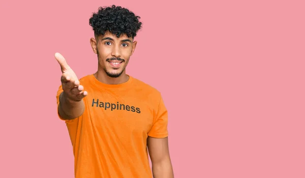 年轻的阿拉伯男子穿着印有快乐字样的T恤 微笑友好地握手致意和欢迎 成功的商业 — 图库照片