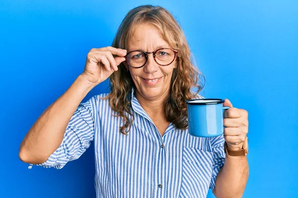 中年金发女人戴着眼镜 喝了一杯咖啡 脸上挂着快乐而凉爽的笑容 显示牙齿 — 图库照片