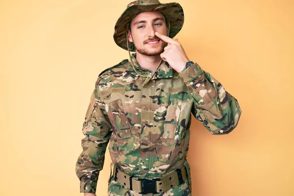 若い白人男性の顔や鼻に手指で指してカモフラージュ軍の制服を着て 陽気な笑顔 美の概念 — ストック写真