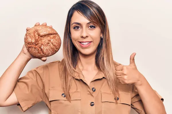 Jovem Bela Mulher Segurando Pão Sorrindo Feliz Positivo Polegar Para — Fotografia de Stock