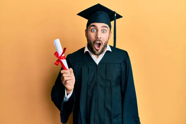 Joven Hombre Hispano Con Bata Graduación Sosteniendo Diploma Asustado Sorprendido — Foto de Stock