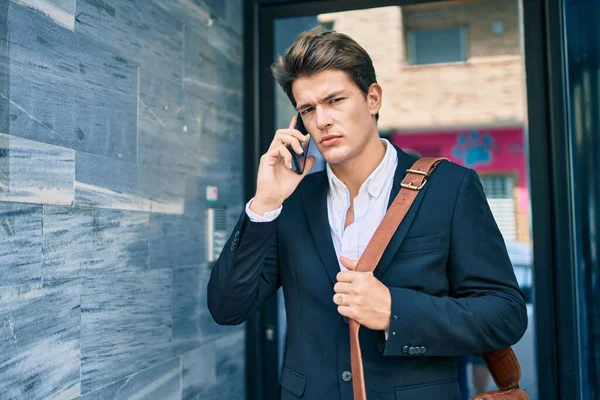 Kafkasyalı genç iş adamı ciddi bir ifadeyle şehirdeki akıllı telefondan konuşuyor..