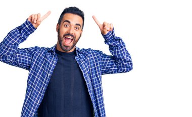 Gündelik kıyafetler giyen genç İspanyol adam şaşırmış, şaşırmış ve parmaklarıyla işaret ediyor ve kollarını kaldırıyordu.. 