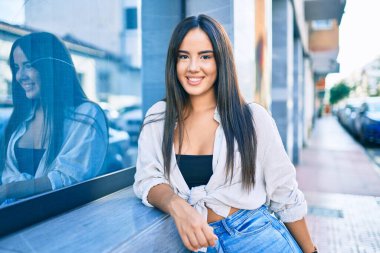 Genç İspanyol kız gülümsüyor. Mutlu bir şekilde şehrin duvarına yaslanıyor..