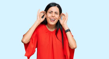 Gündelik giysiler giyen güzel genç bir kadın iki elini de kulak hareketlerini duymaya çalışıyor. Dedikoduya meraklı. İşitme sorunu, sağır 